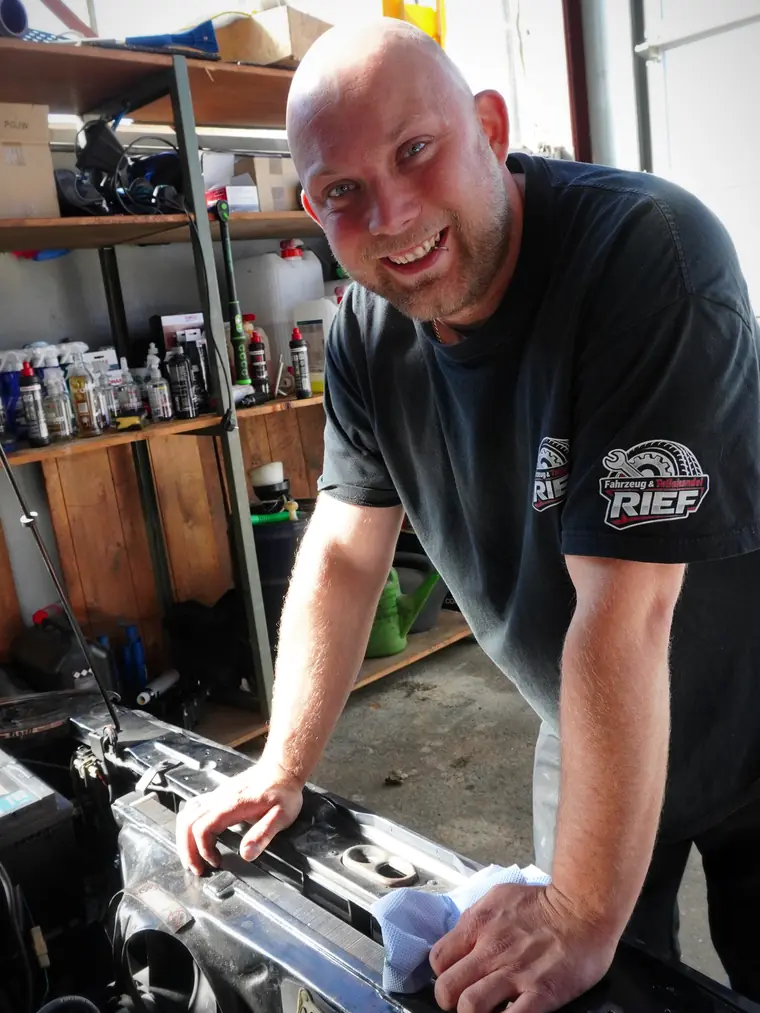 Alexander Rief lacht bei der Arbeit am Motor eines Klassikers