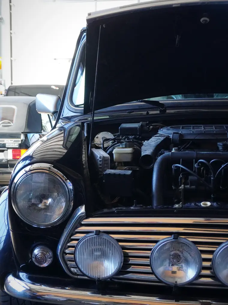 Klassischer Mini mit offener Motorhaube auf der Hebebühne bei Fahrzeug Rief in Maierhöfen